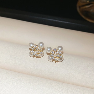 Macro shot of gold firework stud earrings with white pearls and sparkling rhinestones