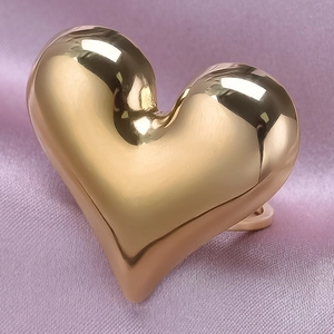 Close-up of a gold 18K plated heart-shaped ring on pink silk fabric background