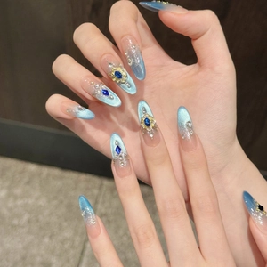 Macro shot of luxury almond-shaped blue cat-eye nails with crystals and gold accents