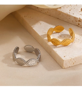 Detail of gold and silver textured open rings on natural stone and cream fabric