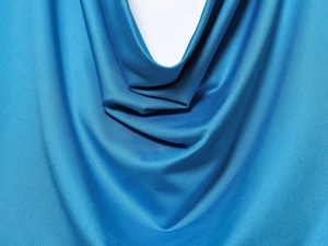Detail of blue satin fabric with elegant drape and smooth synthetic fiber texture