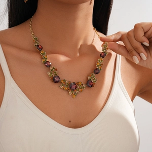 Detail of vintage necklace with purple gemstone and green floral crystal accents
