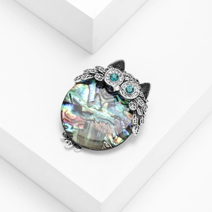 Exquisite owl brooch featuring iridescent abalone shell and sparkling blue gemstone eyes