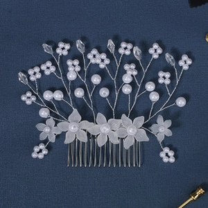 Close-up of handmade bridal hair comb with white pearls and acrylic flowers