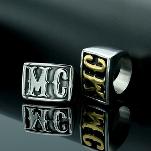 Macro detail of men's punk MC signet ring in silver and two-tone gold on a mirror surface