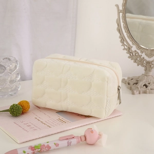 Close-up of quilted cream makeup bag with soft plush texture and secure zipper closure