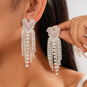 Pink heart tassel earrings with silver rhinestones and long dangling chains on a model