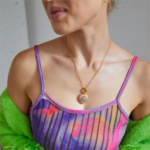 Close-up of heart-shaped locket necklace with colorful crystals on a female model