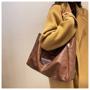 Close-up of a large brown leather tote bag worn with a stylish camel coat