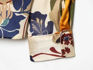 Close-up of buttoned cuff on floral satin shirt with blue and yellow abstract pattern