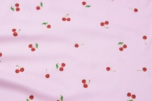 Gros plan sur le tissu en maille côtelée rose avec motifs de cerises rouges et feuilles