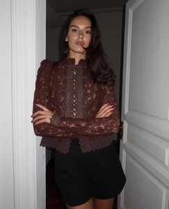 Detalle de blusa de encaje marrón oscuro con cuello mandarín y cierre de nudo tradicional