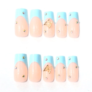 Detail of light blue French press-on nails featuring golden butterflies and rhinestones