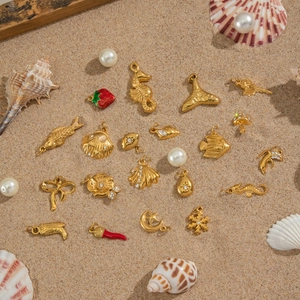 Assorted 18K gold stainless steel sea-themed charms on sand with pearls and shells