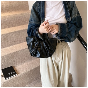 Detail showing a black pleated cloud bag with a soft leather finish and stylish handle