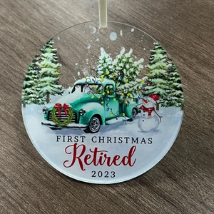 Detail of clear acrylic ornament with a 2023 snowman and vintage truck design