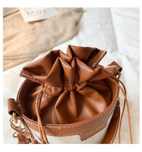 Detailed close-up of a canvas and leather bucket bag with drawstring closure and logo