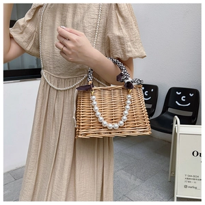 Close-up of handmade woven wicker bag featuring pearl handle and plaid bow accessory