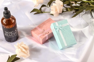 Elegant pink and light blue jewelry gift boxes with ribbons on white silk background