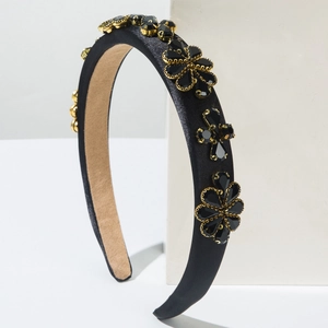 Détail du serre-tête baroque en satin noir avec fleurs en cristal et bords dorés