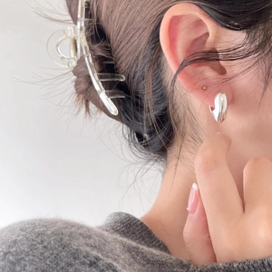 Close-up of sleek liquid metal silver earrings with a smooth polished finish on model