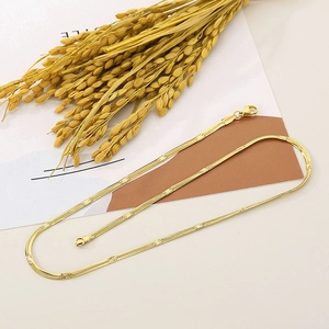 Detail of 2.7mm gold flat snake chain necklace with lobster clasp on a stylish background