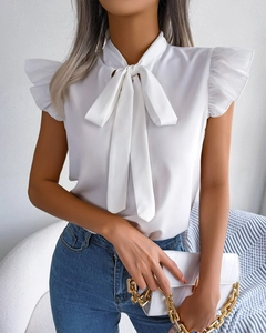 Close-up of white summer blouse featuring ruffle sleeves and a bow-tie neckline detail