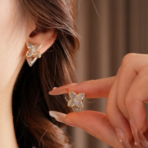 Close-up of four-leaf clover flower earrings with sparkling zircon and silver pendant
