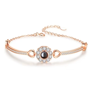 Rose gold projection bracelet with round stone and heart accents on white background