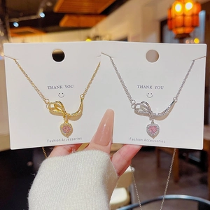 Elegant gold and silver bow necklaces with pink heart pendants on display cards