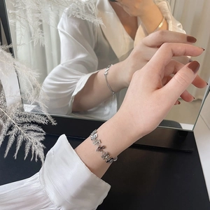 Detail of silver musical note bracelet reflected on mirror surface with refined metal texture