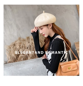 Detail of beige wool beret paired with a geometric knit vest and brown leather bag