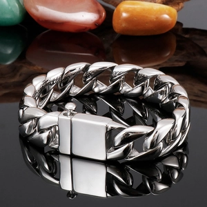 Detailed view of silver Cuban link chain bracelet with square safety clasp on black mirror