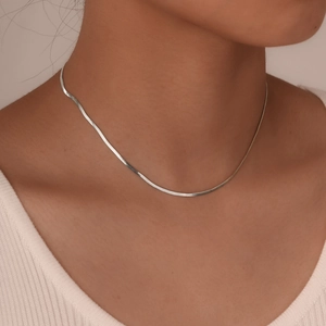 Close-up of polished silver herringbone snake chain necklace on a model's neck