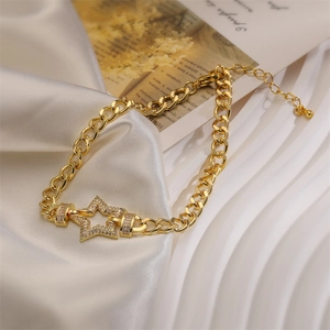 Close-up of golden curb chain bracelet featuring a sparkling pavé star pendant on silk
