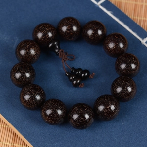 Macro shot of dark blood sandalwood beads with gold silk texture and traditional knot