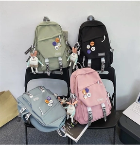 Detail of four colorful school backpacks with decorative badges and rabbit pendants