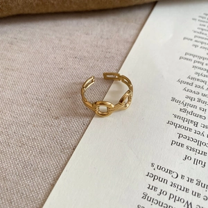 Detail of a gold-plated stainless steel chain link open ring on vintage book pages