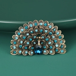 Detailed close-up of a vintage golden peacock brooch with sparkling blue rhinestones