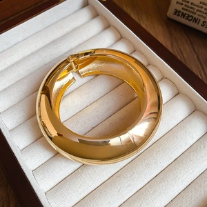 Close-up of a wide golden adjustable cuff bracelet displayed in a premium velvet gift box