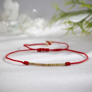 Handmade woven red string bracelet with adjustable wooden beads on a white background