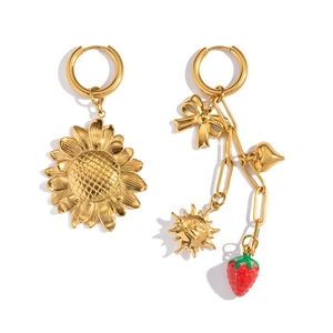 Detailed close-up of gold sunflower and mismatched strawberry charms on earrings