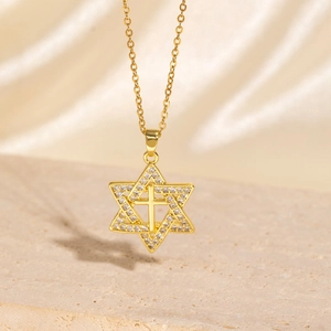 Detail of gold hexagram cross pendant with zircon on stone and silk background