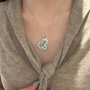 Silver gourd pendant necklace with pearls and blue gemstone on a model in knitwear