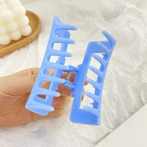 Light blue matte square hollow hair claw clip held by hand with a minimalist aesthetic