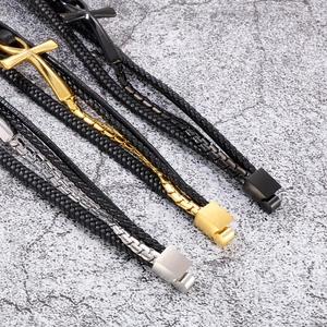 Three multi-layer braided leather bracelets with gold, silver, and black cross pendants