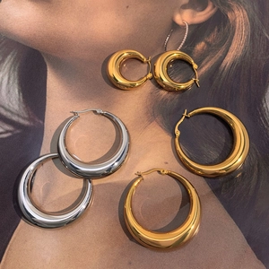 Set aus polierten klobigen Creolen in Gold und Silber auf einem Modemagazin