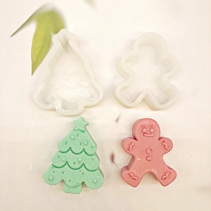 Silicone molds with finished green Christmas tree and pink gingerbread man shapes