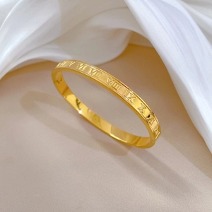 Minimalist gold titanium steel bangle with Roman numerals engraved on polished surface