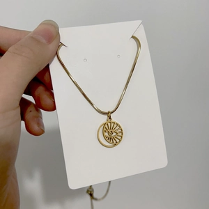 Macro detail of 18K gold evil eye crescent pendant with a sleek snake chain necklace